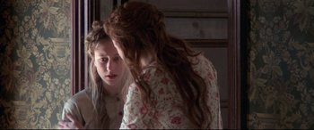 Movie still from “In a Valley of Violence” (2016), directed by Ti West – A woman looking in the mirror while wearing a floral dress; Close Up shot, Over the shoulder angle