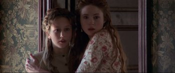 Movie still from “In a Valley of Violence” (2016), directed by Ti West – Two young women standing next to each other in a room; Close Up shot, Over the shoulder angle