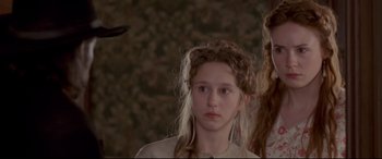 Movie still from “In a Valley of Violence” (2016), directed by Ti West – A young girl is looking at the camera while a younger girl looks at the camera; Close Up shot, Over the shoulder angle