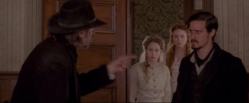 Movie still from “In a Valley of Violence” (2016), directed by Ti West – A man pointing to two girls in a room; Medium shot, Over the shoulder angle