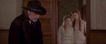 Movie still from “In a Valley of Violence” (2016), directed by Ti West – A man and two girls in a room; Medium shot, Over the shoulder angle