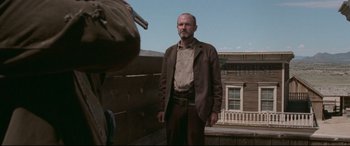 Movie still from “In a Valley of Violence” (2016), directed by Ti West – A man standing on top of a wooden fence; Medium shot, Low angle