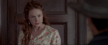 Movie still from “In a Valley of Violence” (2016), directed by Ti West – A young woman with red hair and a floral dress; Close Up shot, Over the shoulder angle
