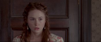 Movie still from “In a Valley of Violence” (2016), directed by Ti West – A young woman with long red hair wearing a floral dress; Close Up shot, High angle