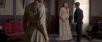 Movie still from “In a Valley of Violence” (2016), directed by Ti West – A woman in a long dress standing in front of a mirror; Medium shot, Over the shoulder angle