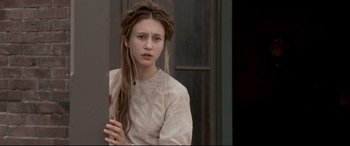 Movie still from “In a Valley of Violence” (2016), directed by Ti West – A young woman with long brown hair wearing a white dress; Close Up shot, Over the shoulder angle