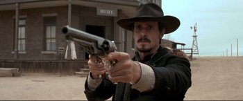 Movie still from “In a Valley of Violence” (2016), directed by Ti West – A man in a hat is holding a gun; Close Up shot, Low angle