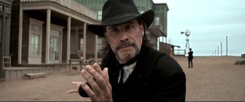 Movie still from “In a Valley of Violence” (2016), directed by Ti West – A man in a black hat claps his hands; Close Up shot, Low angle