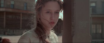 Movie still from “In a Valley of Violence” (2016), directed by Ti West – A young woman with long brown plaits looking at the camera; Close Up shot, Low angle