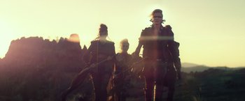 A group of people walking across a field at sunset
