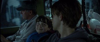 Movie still from “In the Bedroom” (2001), directed by Todd Field – A young boy sitting on a bus with his parents; Close Up shot, Over the shoulder angle