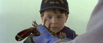 Movie still from “In the Bedroom” (2001), directed by Todd Field – A young boy wearing a baseball cap holding a crab; Close Up shot, Low angle