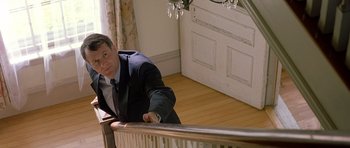 Movie still from “In the Bedroom” (2001), directed by Todd Field – A man leaning on a railing in front of a window; Medium shot, High angle