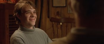 Movie still from “In the Bedroom” (2001), directed by Todd Field – A young man smiling while sitting in a chair; Close Up shot, Over the shoulder angle