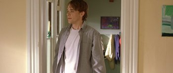 Movie still from “In the Bedroom” (2001), directed by Todd Field – A young man standing in a room with his hands in his pockets; Medium shot, Over the shoulder angle
