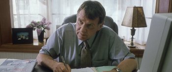 Movie still from “In the Bedroom” (2001), directed by Todd Field – A man sitting at a desk writing on a piece of paper; Close Up shot, Low angle