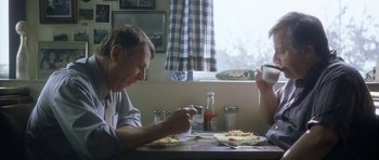 Movie still from “In the Bedroom” (2001), directed by Todd Field – Two people sitting at a table eating pizza; Medium shot, Low angle