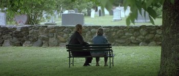 Movie still from “In the Bedroom” (2001), directed by Todd Field – A man and woman sitting on top of a park bench; Wide shot, High angle