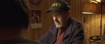 Movie still from “In the Bedroom” (2001), directed by Todd Field – An older man wearing a navy hat sitting at a table; Close Up shot, Over the shoulder angle