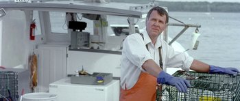 Movie still from “In the Bedroom” (2001), directed by Todd Field – A man wearing an apron and gloves in a kitchen; Medium shot, Low angle
