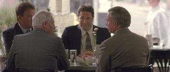 Movie still from “In the Bedroom” (2001), directed by Todd Field – A group of men sitting at a table talking to each other; Medium shot, Over the shoulder angle