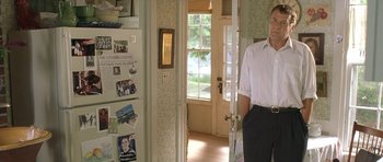 Movie still from “In the Bedroom” (2001), directed by Todd Field – A man standing in front of an open door in a house; Medium shot, Over the shoulder angle