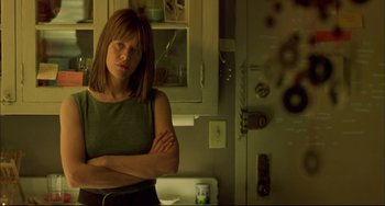 Movie still from “In the Cut” (2003), directed by Jane Campion – A woman standing with her arms crossed in a kitchen; Medium shot, Low angle