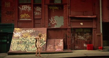 Movie still from “In the Cut” (2003), directed by Jane Campion – A woman standing in front of a building with graffiti on it; Extreme Wide shot, Low angle
