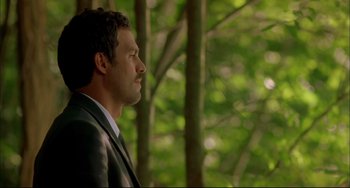 Movie still from “In the Cut” (2003), directed by Jane Campion – A person wearing a suit near a tree; Close Up shot, Over the shoulder angle