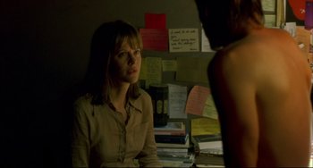 Movie still from “In the Cut” (2003), directed by Jane Campion – A woman sitting at a desk in front of a wall covered with papers; Medium shot, Over the shoulder angle