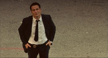 Movie still from “In the Cut” (2003), directed by Jane Campion – A man in a suit and tie posing for a picture; Medium shot, Low angle