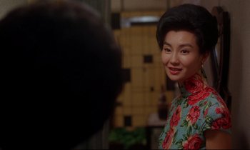 Movie still from “In the Mood for Love” (2000), directed by Kar-Wai Wong – A woman in a floral dress smiling for the camera; Close Up shot, Over the shoulder angle