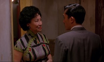Movie still from “In the Mood for Love” (2000), directed by Kar-Wai Wong – An older woman standing next to a younger man; Medium shot, Over the shoulder angle