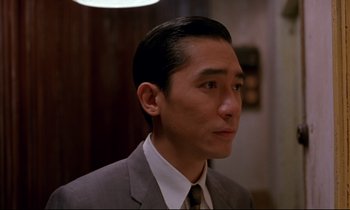 Movie still from “In the Mood for Love” (2000), directed by Kar-Wai Wong – A person wearing a suit and tie; Close Up shot, Over the shoulder angle