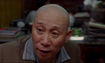 Movie still from “In the Mood for Love” (2000), directed by Kar-Wai Wong – An older man with a bald head looking at the camera; Close Up shot, Over the shoulder angle