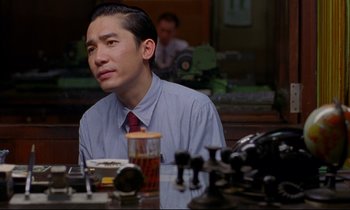 Movie still from “In the Mood for Love” (2000), directed by Kar-Wai Wong – A man sitting at a dinner table looking off into the distance; Close Up shot, Low angle