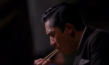 Movie still from “In the Mood for Love” (2000), directed by Kar-Wai Wong – A person with chopsticks in their mouth; Close Up shot, High angle