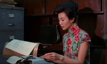 Movie still from “In the Mood for Love” (2000), directed by Kar-Wai Wong – A woman sitting at a desk in front of a sheet of music; Medium shot, High angle