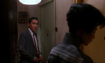 Movie still from “In the Mood for Love” (2000), directed by Kar-Wai Wong – A man standing in front of a mirror in a room; Medium shot, Over the shoulder angle