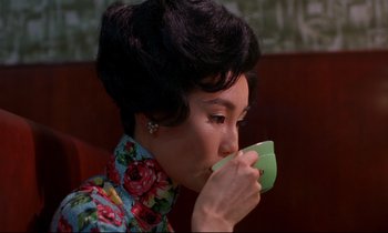 Movie still from “In the Mood for Love” (2000), directed by Kar-Wai Wong – A woman is drinking a cup of coffee; Close Up shot, High angle