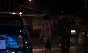 Movie still from “In the Mood for Love” (2000), directed by Kar-Wai Wong – A man and a woman walking down a street; Wide shot, Over the shoulder angle