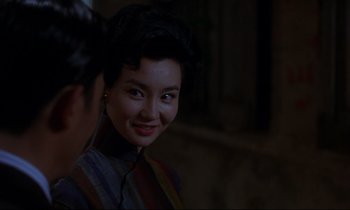 Movie still from “In the Mood for Love” (2000), directed by Kar-Wai Wong – A woman smiles brightly while standing next to another woman; Close Up shot, Over the shoulder angle