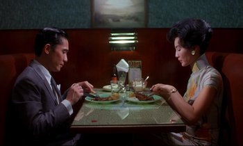 Movie still from “In the Mood for Love” (2000), directed by Kar-Wai Wong – A man and a woman sitting at a dinner table; Medium shot, High angle