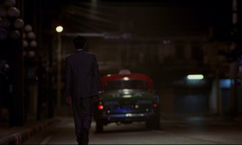 Movie still from “In the Mood for Love” (2000), directed by Kar-Wai Wong – A man in a suit walking down the street; Wide shot, Low angle