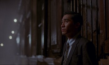 Movie still from “In the Mood for Love” (2000), directed by Kar-Wai Wong – A man wearing a suit and tie looking off into the distance; Medium shot, Low angle