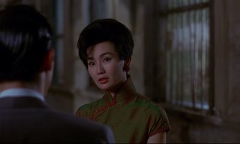 Movie still from “In the Mood for Love” (2000), directed by Kar-Wai Wong – A woman in a green dress is standing in front of a man; Close Up shot, Over the shoulder angle