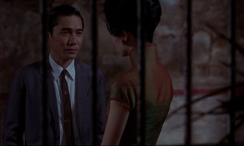 Movie still from “In the Mood for Love” (2000), directed by Kar-Wai Wong – A man and a woman standing next to each other in front of bars; Medium shot, Over the shoulder angle