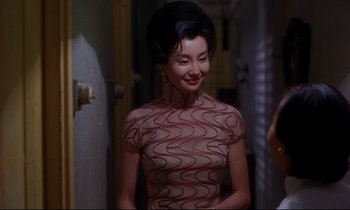 Movie still from “In the Mood for Love” (2000), directed by Kar-Wai Wong – A woman in a dress smiling for the camera; Medium shot, Over the shoulder angle