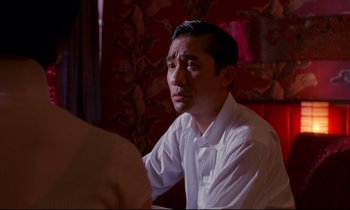 Movie still from “In the Mood for Love” (2000), directed by Kar-Wai Wong – A man sitting in front of a woman at a table; Close Up shot, Over the shoulder angle