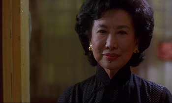 Movie still from “In the Mood for Love” (2000), directed by Kar-Wai Wong – An older asian woman wearing a black shirt and gold earrings; Close Up shot, Low angle
